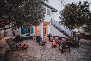 una casa y un patio con sillas y mesas. en Dalmatian Stone House, en Preko