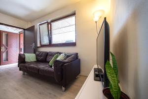 a living room with a brown couch and a tv at Apartman MANDALA in Banská Bystrica