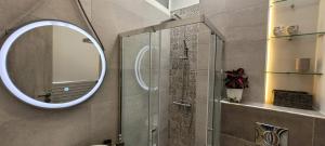 ein Bad mit einem Spiegel und einer Dusche in der Unterkunft Gregory's Apartment in Néa Palátia
