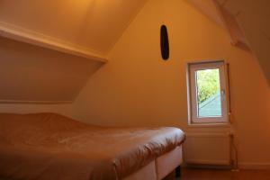1 dormitorio con cama y ventana en Schwone Diekhuusje - Vakantiewoning aan de Noordzeekust, en Schoondijke