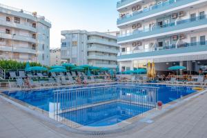 a swimming pool with chairs and umbrellas next to a hotel at Mesut Hotel in Alanya