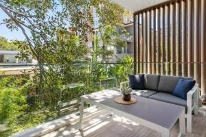 a patio with a couch and a table on a balcony at Azure Apartments by Urban Rest in Sydney