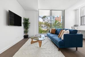 雪梨的住宿－Azure Apartments by Urban Rest，客厅配有蓝色的沙发和桌子