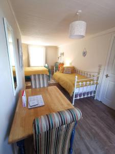 ein Schlafzimmer mit einem Bett und einem Holztisch mit einem Esszimmer in der Unterkunft The Nook @ Rowan Tree Cottage in Ballymoney