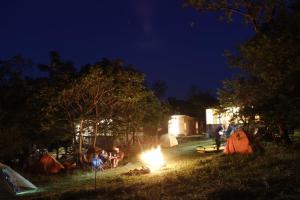 grupa ludzi siedzących w nocy przy ognisku w obiekcie Sveri Adventure Camp w mieście Chiatʼura