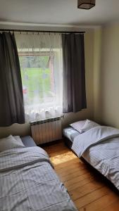 2 camas en una habitación con ventana en Agroturystyka "RYVILLA" en Gaboń