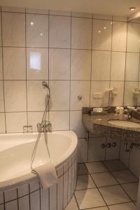 ein Badezimmer mit einer Badewanne und einem Waschbecken in der Unterkunft Stadt-Gut-Hotel Zum Rathaus in Oberhausen