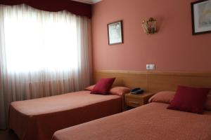 two beds in a room with red walls and a window at Hotel Rego Foz in Foz