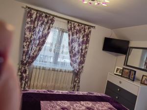 - une chambre avec un lit violet et une fenêtre dans l'établissement Casa Luca, à Vama