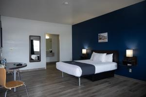 - une chambre avec un grand lit et un mur bleu dans l'établissement The Beaverhead Lodge, à Dillon