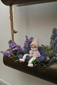una muñeca pequeña sentada en un estante con flores púrpuras en Vaskó Panzió Borpince, en Tokaj