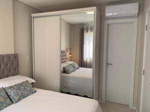 a mirror in a bedroom with two beds and a mirror at Suíte Master Collection in Passo Fundo