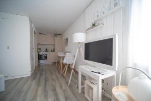 Ein weißes Wohnzimmer mit Fernseher und Schreibtisch in der Unterkunft Studio Living... in Langnau im Emmental