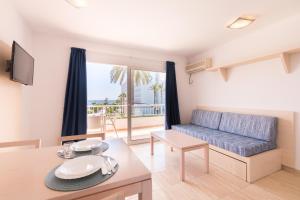 a living room with a blue couch and a table at Apartamentos Vistamar I - MC Apartamentos Ibiza in Playa d'en Bossa