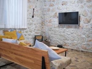 a living room with a couch and a tv on a stone wall at Seaside Duplex Stone Villa in Qeparo