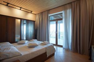 a bedroom with a large bed and a large window at Seaside Duplex Stone Villa in Qeparo
