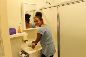 a woman standing in a bathroom brushing her teeth at Venice Beach Hostel in Los Angeles