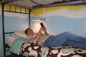 ロサンゼルスにあるベニス ビーチ ホステルの携帯で寝転がって写真を撮っている男