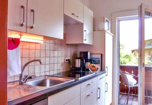 Haus Waldfriede في ويسينسي: مطبخ مع دواليب بيضاء ومغسلة