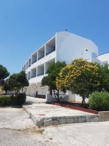 a white building with trees in front of it at Lilly Apartment in Faliraki