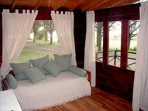 a bedroom with a white bed and a window at Estancia Laguna Vitel in Chascomús