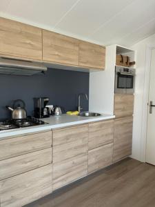 a kitchen with wooden cabinets and a stove top oven at Wad Mooi in Tzummarum