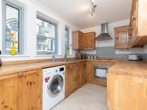 cocina con armarios de madera, lavadora y secadora en Pass the Keys Bright modern one bed apartment - Bath city centre, en Bath