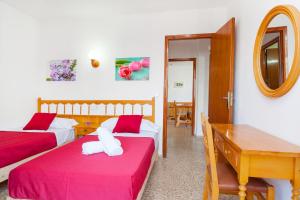 a bedroom with two beds and a table and a mirror at Apartamentos Puet in San Antonio