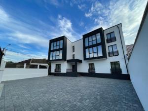 a white house with black windows and a brick driveway at Concept Apartments Budiului 42 in Târgu-Mureş