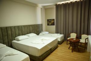 a hotel room with two beds and a table and chairs at Fjortes Palace in Vlorë