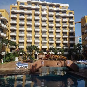 uma piscina em frente a um hotel com um edifício em Hotel Margarita Dynasty em Porlamar