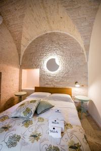 ein Schlafzimmer mit einem großen Bett und einer Steinmauer in der Unterkunft Petra Suite in Alberobello