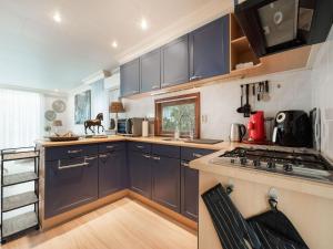 uma cozinha com armários azuis e um forno com placa de fogão em Urbane Holiday Home in Garderen with Terrace and Garden em Garderen