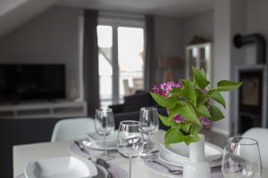 een tafel met glazen en een vaas met paarse bloemen bij moderne Neubau-Wohnung mit Kamin und 35qm Dachterrasse in Trossingen