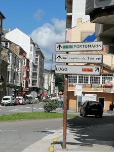 a pole with street signs on a city street at Cuatro Caminos in Sarria