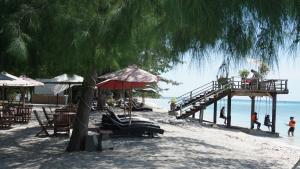 una spiaggia con tavoli e ombrelloni e un molo di Wah Resort Gili Trawangan a Gili Trawangan