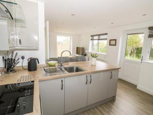 a kitchen with white cabinets and a sink at Meadow Cottage in Broadway