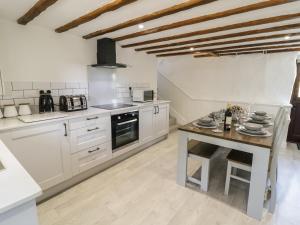 cocina con armarios blancos y mesa de madera en Cyffdy Cottage - Arenig en Bala