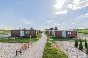 une rangée de maisons sur la plage avec des bancs dans l'établissement Twój Zakątek pod Zatorem, à Zator