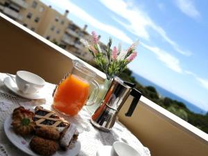 Voce Del Mare - sea view- Alghero Airport في ألغيرو: طاولة مع وجبة إفطار من عصير البرتقال والبسكويت