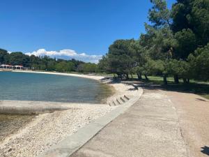 una playa con árboles y un camino junto al agua en Apartment Luca, en Pula