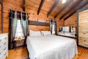 ein Schlafzimmer mit einem weißen Bett in einem Zimmer mit Holzwänden in der Unterkunft Idlewild in Sautee Nacoochee