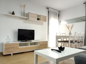 a living room with a tv and a white table at Apartamentos Coralba - El Escondite de la Bahía in San Fernando