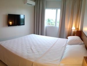 a bedroom with a white bed with a television on the wall at Salinas Exclusive Resort - 402-II in Salinópolis