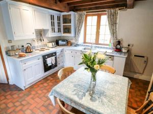 una cocina con una mesa con un jarrón de flores. en Slade Cottage en Ashbourne