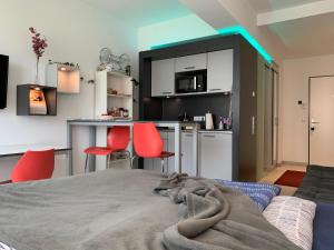 Habitación con cama y cocina con sillas rojas. en Exklusive Wohlfühloase by Rabe - Parkplatz & free Netflix & Coffee-Bar en Karlsruhe