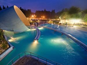 ein großes Schwimmbecken mit blauem Wasser bei Nacht in der Unterkunft Hotel Szeleta in Lillafüred