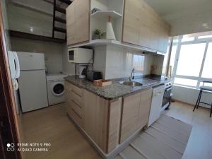 a small kitchen with a sink and a refrigerator at Apartamento S. João da Foz in Porto