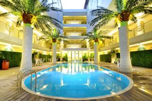 a large pool with palm trees in a building at Sun Boutique Hotel in Kuta