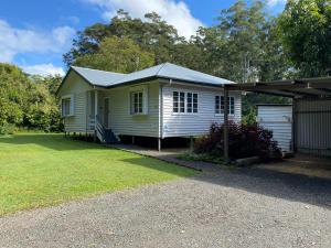 a small yellow house with a garage at Coochin Cottage, Beerwah in Beerwah